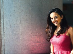Photo of Paula Pant against a silver wall in pink dress